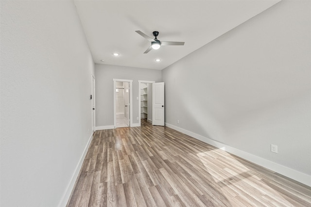 unfurnished bedroom featuring connected bathroom, baseboards, light wood-style floors, and a ceiling fan