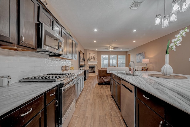 kitchen with visible vents, backsplash, light wood-type flooring, appliances with stainless steel finishes, and a sink