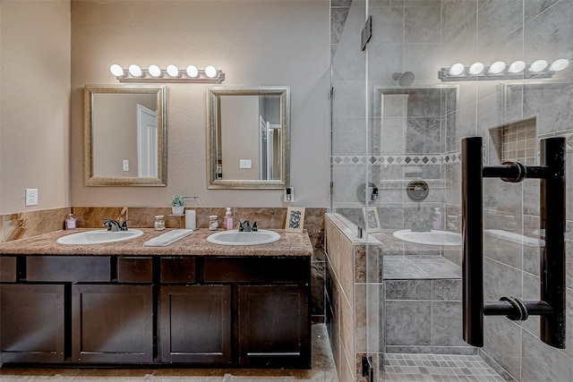 full bathroom with double vanity, a stall shower, and a sink