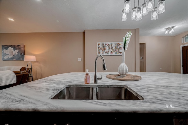 kitchen with open floor plan, light stone countertops, and a sink