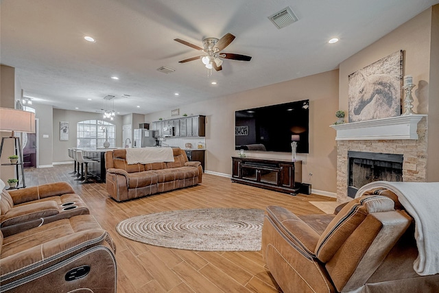 living area featuring light wood-type flooring, visible vents, recessed lighting, and a fireplace