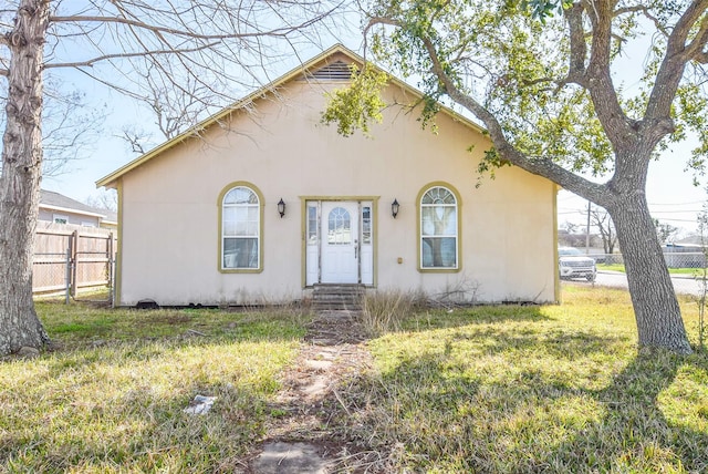 view of front of property featuring stucco siding, a front yard, and fence