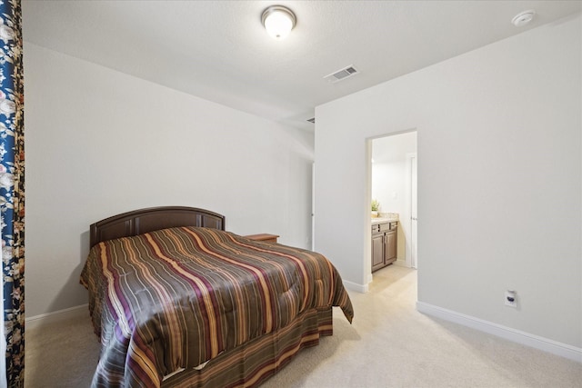 bedroom with visible vents, light carpet, baseboards, and ensuite bath