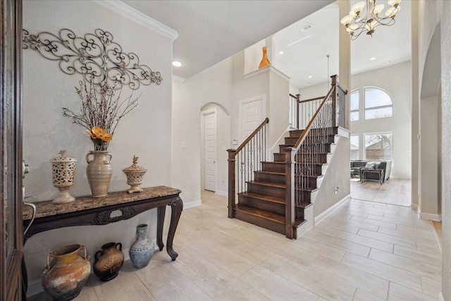 entrance foyer featuring stairs, baseboards, arched walkways, and a chandelier