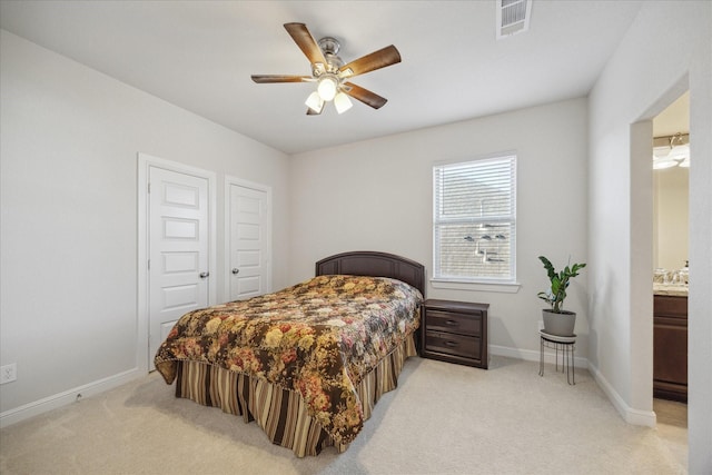 bedroom featuring ensuite bath, light colored carpet, visible vents, and baseboards