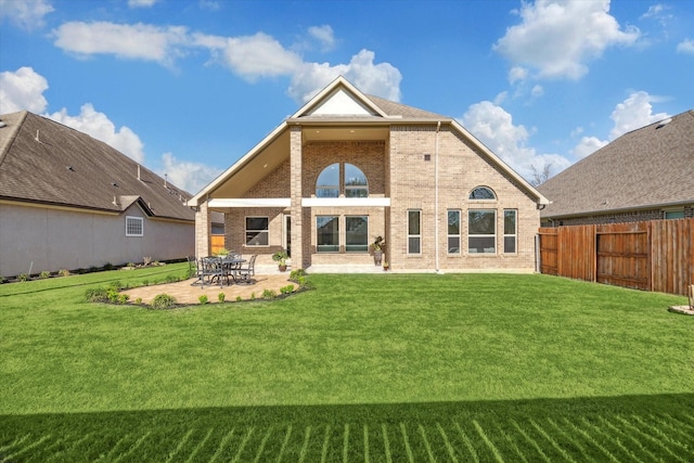 back of house featuring a yard, a patio, brick siding, and fence