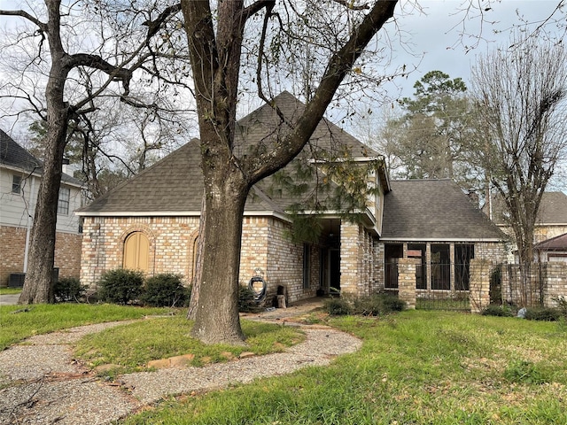 french country home featuring a front yard, brick siding, and roof with shingles