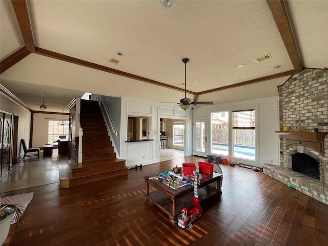 living room featuring lofted ceiling with beams, visible vents, wood finished floors, and a fireplace