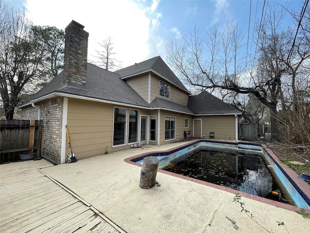 back of property featuring fence, a fenced in pool, and a shingled roof