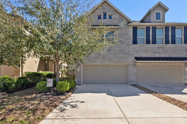 townhome / multi-family property featuring a garage, stone siding, and driveway