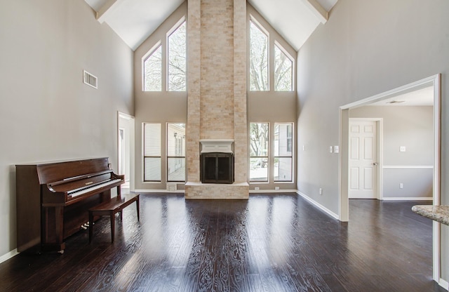 living area with a wealth of natural light, visible vents, dark wood-style flooring, and a large fireplace