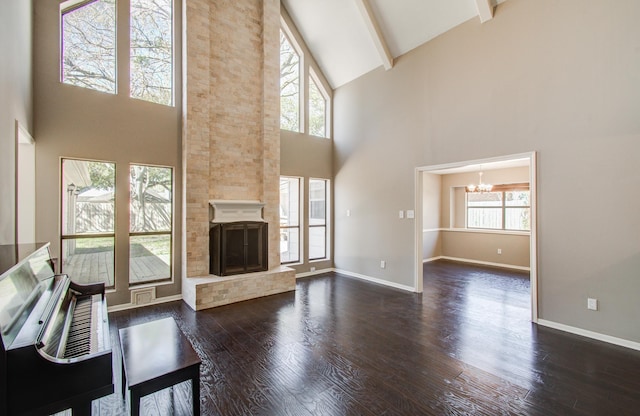 unfurnished living room featuring baseboards, a chandelier, lofted ceiling with beams, a fireplace, and dark wood-style flooring