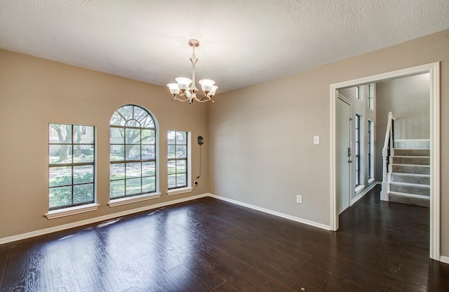 spare room featuring a chandelier, dark wood-style floors, stairway, and baseboards