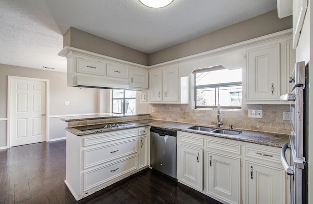 kitchen with a peninsula, dark wood-style flooring, a sink, stainless steel dishwasher, and black electric stovetop