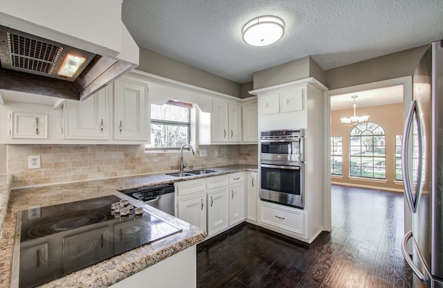 kitchen with a sink, dark wood finished floors, appliances with stainless steel finishes, white cabinets, and a healthy amount of sunlight