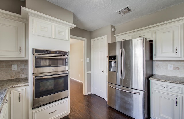 kitchen featuring visible vents, backsplash, dark wood finished floors, white cabinets, and stainless steel appliances