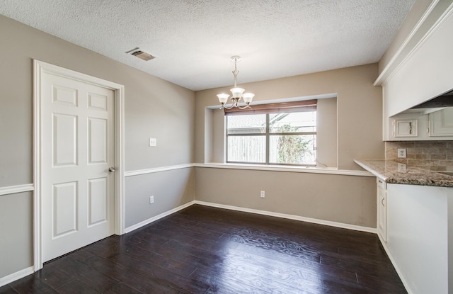 unfurnished dining area with an inviting chandelier, dark wood-style floors, baseboards, and visible vents