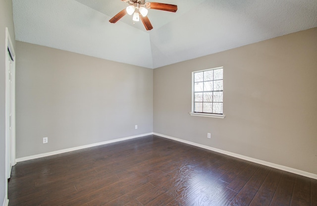 spare room featuring dark wood-style floors, a ceiling fan, lofted ceiling, and baseboards