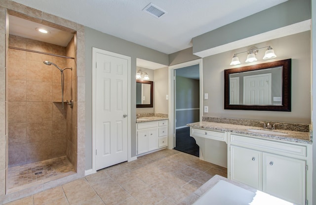 bathroom featuring a tile shower, visible vents, and a sink