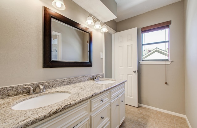 full bathroom with a sink, baseboards, double vanity, and tile patterned floors