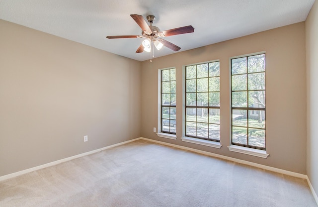 carpeted empty room with baseboards, a healthy amount of sunlight, and a ceiling fan