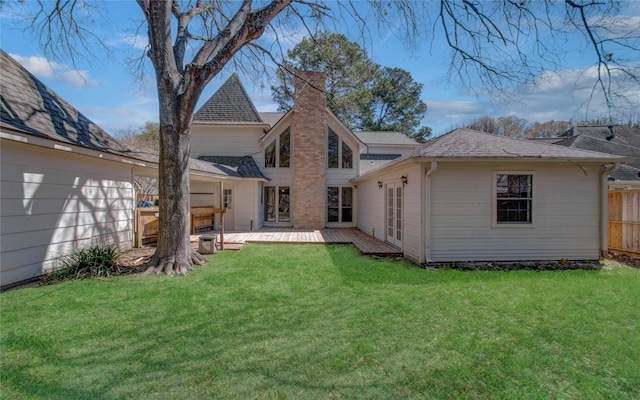 rear view of property with a deck, a lawn, fence, and a chimney