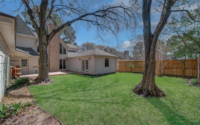 view of yard with a deck, a fenced backyard, and french doors