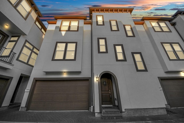 view of property featuring stucco siding, decorative driveway, and a garage