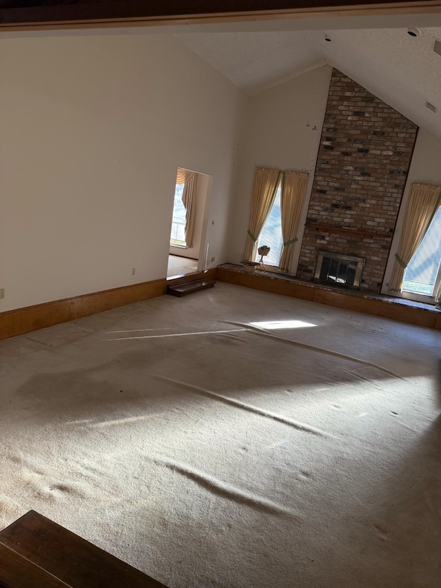 unfurnished living room featuring carpet flooring, a fireplace, high vaulted ceiling, and baseboards