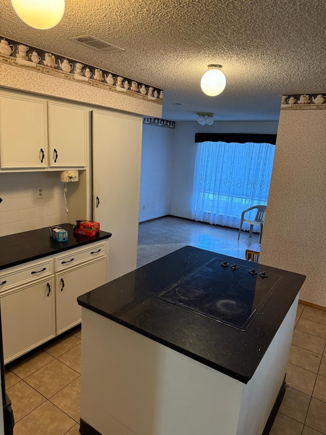 kitchen with wallpapered walls, white cabinets, a textured ceiling, dark countertops, and black electric stovetop