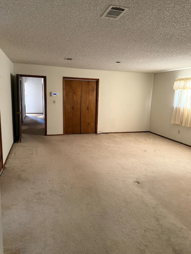 unfurnished bedroom with light colored carpet, visible vents, and a textured ceiling