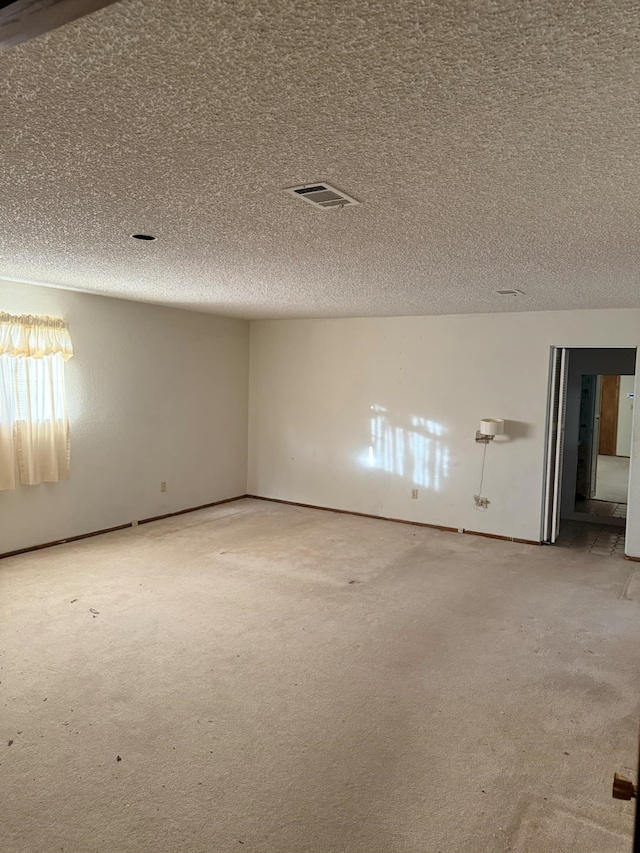 carpeted spare room with visible vents and a textured ceiling