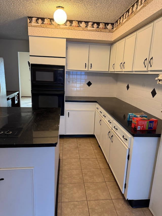 kitchen featuring dark countertops, light tile patterned floors, white cabinetry, and black appliances