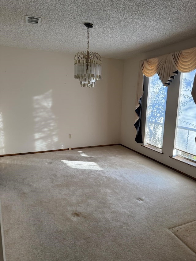 empty room featuring baseboards, visible vents, carpet floors, a textured ceiling, and a notable chandelier