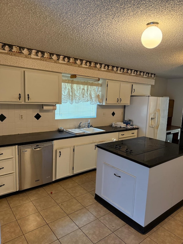 kitchen with dark countertops, stainless steel dishwasher, white fridge with ice dispenser, white cabinetry, and a sink