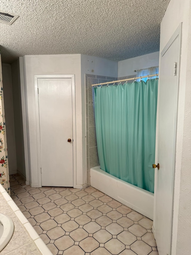 bathroom with shower / bath combo with shower curtain, visible vents, and a textured ceiling