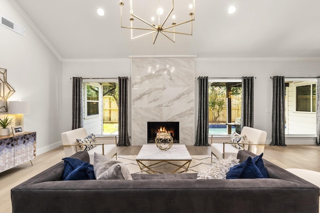 living area with visible vents, plenty of natural light, wood finished floors, a high end fireplace, and an inviting chandelier