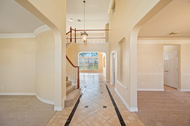 foyer with crown molding, a high ceiling, arched walkways, and baseboards