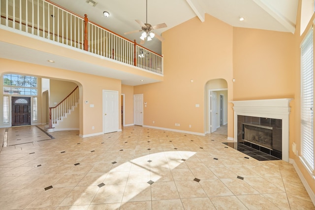 unfurnished living room featuring arched walkways, beamed ceiling, and baseboards