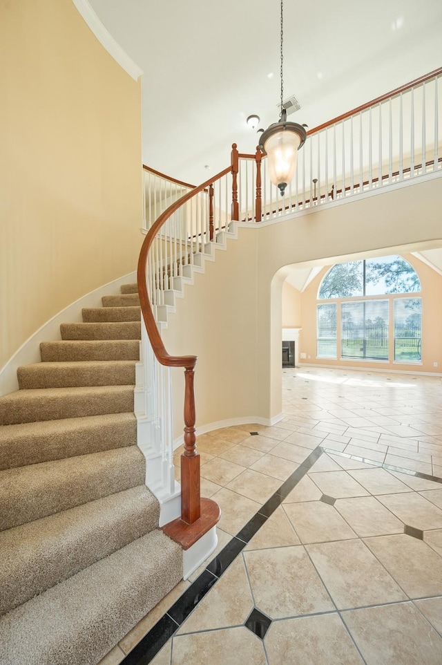 stairs with tile patterned flooring, arched walkways, baseboards, and a towering ceiling