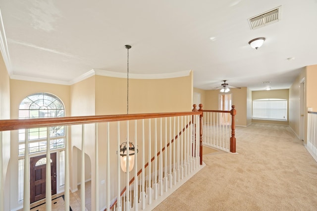 hallway featuring visible vents, baseboards, carpet, ornamental molding, and an upstairs landing