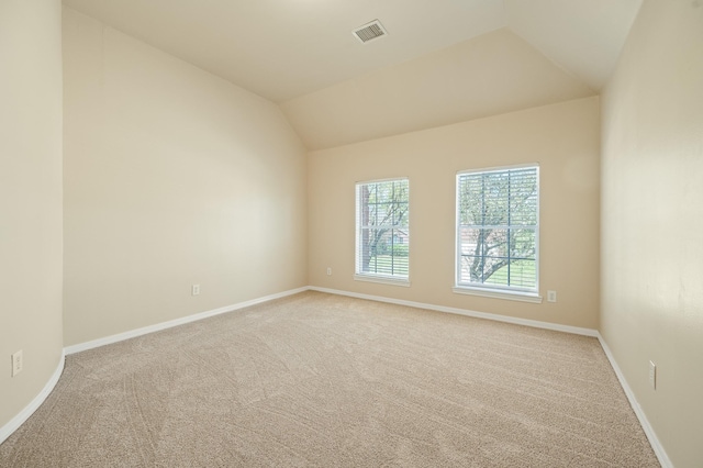 carpeted spare room featuring lofted ceiling, visible vents, and baseboards