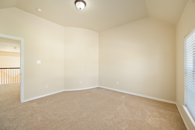 empty room with light colored carpet, baseboards, and lofted ceiling