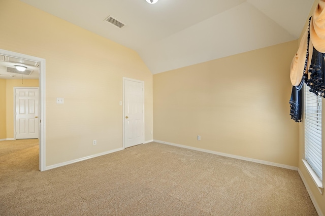 unfurnished room featuring visible vents, baseboards, attic access, lofted ceiling, and light carpet