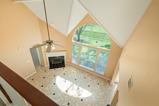 unfurnished living room with visible vents, baseboards, high vaulted ceiling, a fireplace, and tile patterned floors