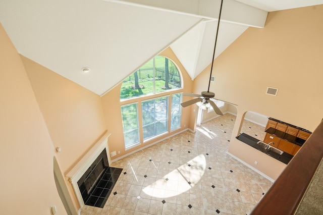 unfurnished living room featuring baseboards, high vaulted ceiling, ceiling fan, tile patterned flooring, and a tiled fireplace