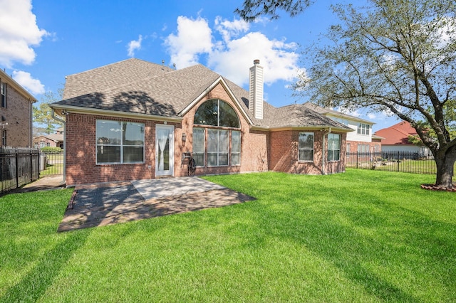 rear view of house with brick siding, a chimney, a fenced backyard, and a lawn