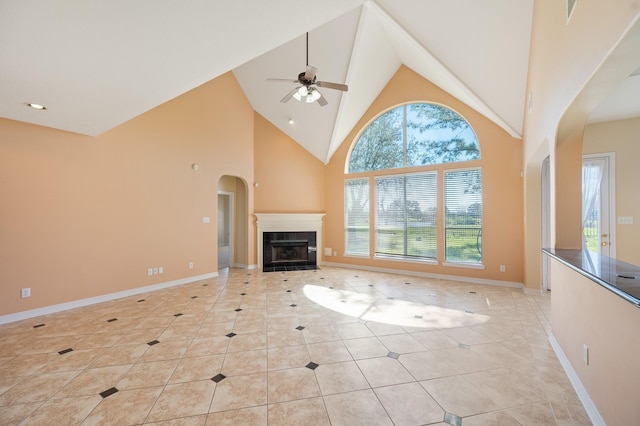 unfurnished living room with high vaulted ceiling, arched walkways, a fireplace, light tile patterned floors, and baseboards