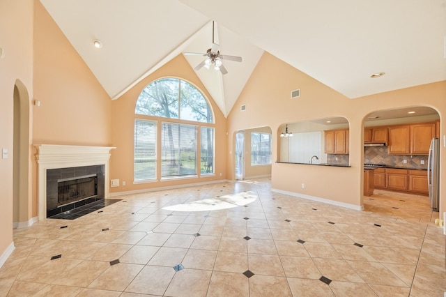 unfurnished living room with light tile patterned floors, baseboards, visible vents, ceiling fan, and a tile fireplace