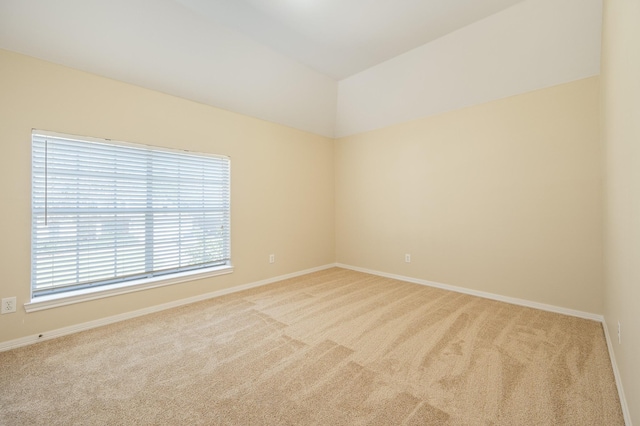 carpeted empty room featuring baseboards and vaulted ceiling